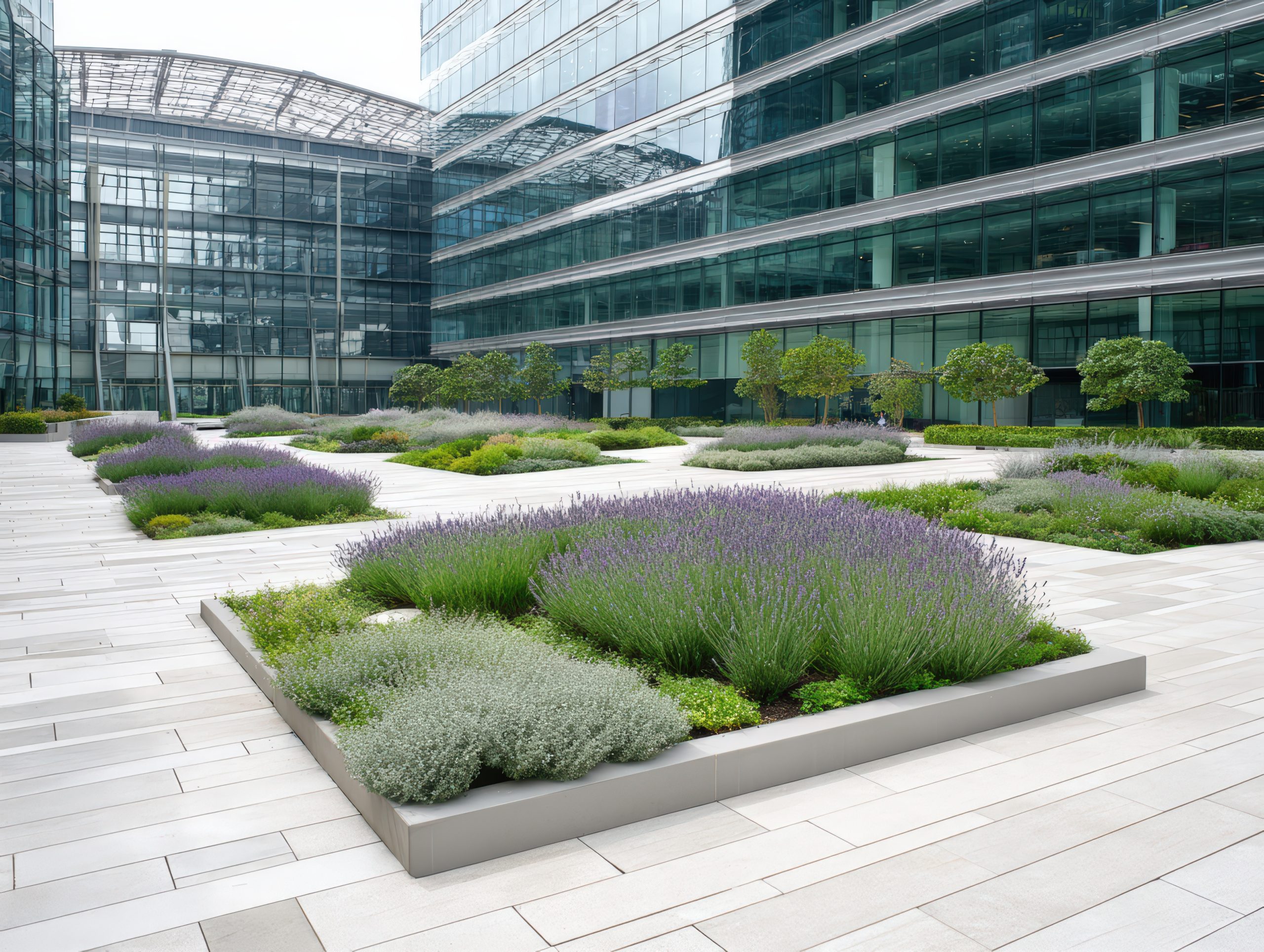 Modern office building with landscaped courtyard featu flower beds and greenery in a tranquil urban setting on a sunny day with clear blue sky.